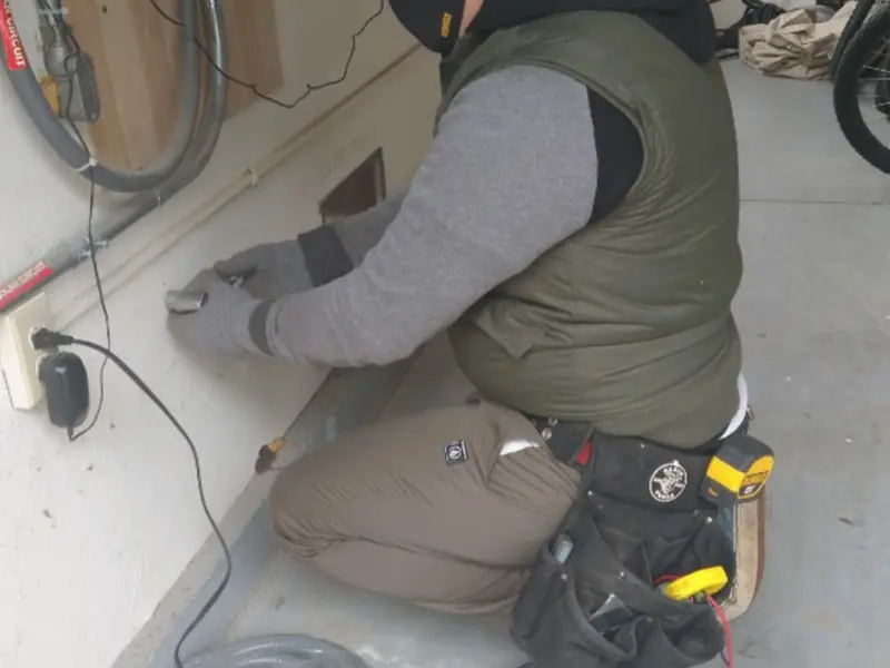 Electrician performing outlet wiring in a Northwood garage